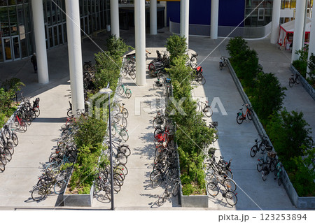 Rows of parked bikes at urban parking in Copenhagen, Denmark. Outdoor bicycle parking area surrounded by plants and modern architecture. Concept of eco-friendly transportation 123253894
