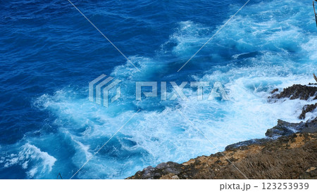 Turquoise ocean sea water white wave splashing deep blue sea. Bird eye view monster wave splash on rock. Tropical sea beach in summer seaside outdoor. Ocean island beautiful dramatic landscape. 123253939