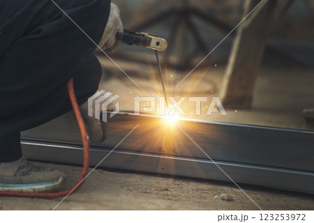 Construction Worker hands using Welding machinery iron metal sparking. Men hands wear protective glove Hot flame metal work cutting fire iron workshop. Locksmith use Welding machine cut metal process 123253972