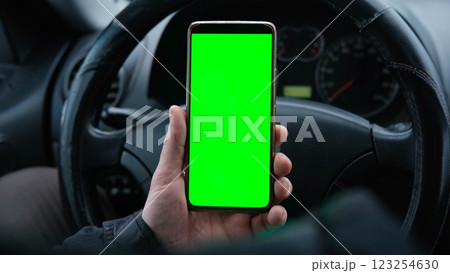 Man using phone with blank green background while driving. Road safety. Automotive technologies. GPS navigation. Mobile applications for drivers. Using gadgets while driving. Smartphone chroma key Man using phone with blank green background while driving. Road safety. Automotive technologies. GPS navigation. Mobile applications for drivers. Using gadgets while driving. Smartphone chroma key 123254630
