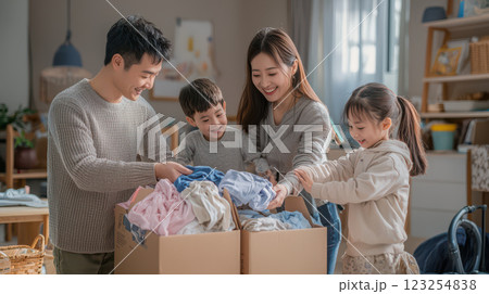 Family packing clothes into donation boxes at home, sharing joy together 123254838