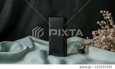 Elegant black packaging on soft fabric with dried flowers in background 123255205