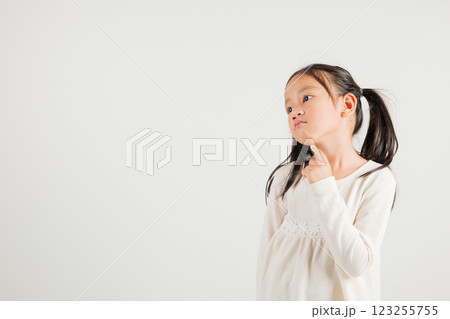 Portrait Asian kid girl deep in thought, standing with chin in hand, pondering a question. Studio shot isolated on white with ample copy space, kindergarten child portraying contemplative expression Portrait Asian kid girl deep in thought, standing with chin in hand, pondering a question. Studio shot isolated on white with ample copy space, kindergarten child portraying contemplative expression 123255755