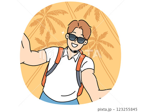 Man tourist in sunglasses takes selfie traveling to hot resort or sunny beach with palm trees 123255845