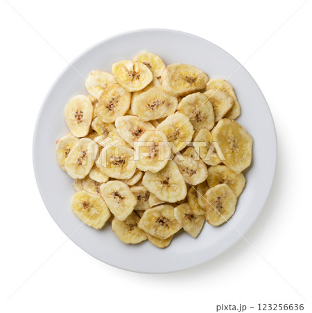 Pile of dried banana chips in a plate close-up on a white background. Top view. Pile of dried banana chips in a plate close-up on a white background. Top view. 123256636