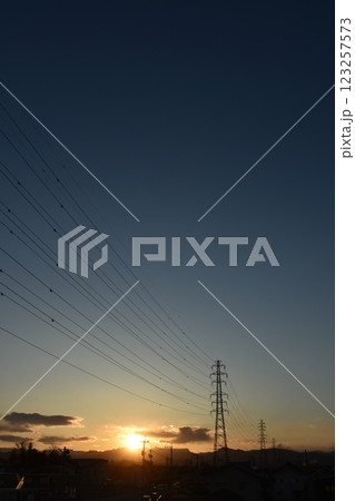 夕暮れ時の山の向こうに見える送電線と鉄塔 123257573