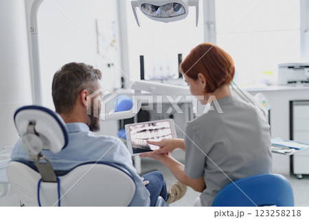 Female dentist showing x-ray to patient in dental clinic during anual check-up. 123258218
