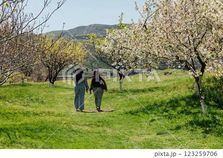 Two women walking in a blooming green garden in spring 123259706