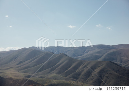 A beautiful landscape of snow-capped mountains and green meadows and a sky with clouds 123259715