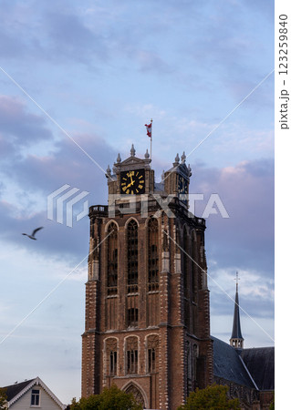 A majestic Gothic church under a dramatic cloudy sky. The intricate brickwork, towering windows, and clock tower reflect its historic architecture and timeless grandeur. 123259840