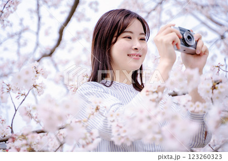 カメラで桜を撮る若い女性 123260323