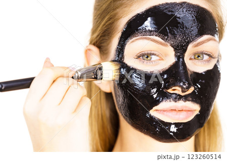 Woman applying black mud mask to face Woman applying black mud mask to face 123260514