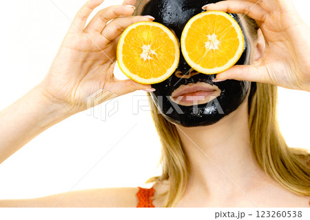Girl black carbo mask on face holds orange fruit 123260538