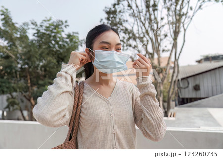 Concerned woman wearing a mask outdoors, highlighting the effects of pollution. Concerned woman wearing a mask outdoors, highlighting the effects of pollution. 123260735