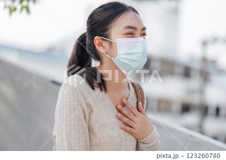 Cheerful woman in a mask smiling while using her smartphone, promoting health and safety in polluted areas. Cheerful woman in a mask smiling while using her smartphone, promoting health and safety in polluted areas. 123260780