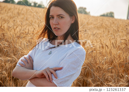 Young woman standing in wheat field at sunset for rural lifestyle concept. Harvesting concept Young woman standing in wheat field at sunset for rural lifestyle concept. Harvesting concept 123261337