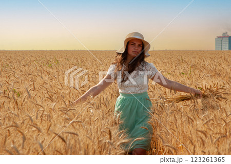 Woman in summer dress walking through wheat field. Harvesting concept Woman in summer dress walking through wheat field. Harvesting concept 123261365