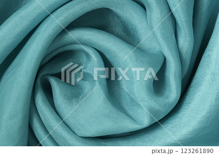 Close-up of turquoise silk fabric with soft folds and flowing texture 123261890