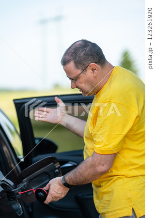 worried and emotional man at open car fuel tank, fuel price rise concept 123261920
