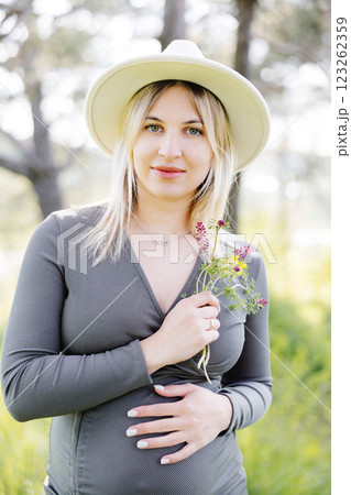 Beautiful pregnant woman in hat and dress walking in the forest. Woman expecting baby born. Beautiful pregnant woman in hat and dress walking in the forest. Woman expecting baby born. 123262359