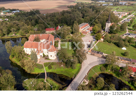 Aerial View of a Castle Surrounded by Water and Trees in Jaunpils, Latvia Aerial View of a Castle Surrounded by Water and Trees in Jaunpils, Latvia 123262544