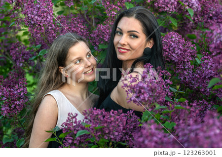 Woman and sister posing in lilac garden. Shallow depth of feld 123263001