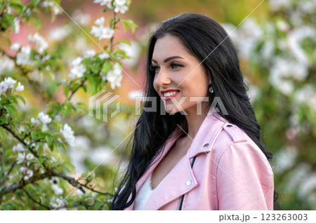 Woman in pink jacket near blooming tree. Background with selective focus and copy space 123263003