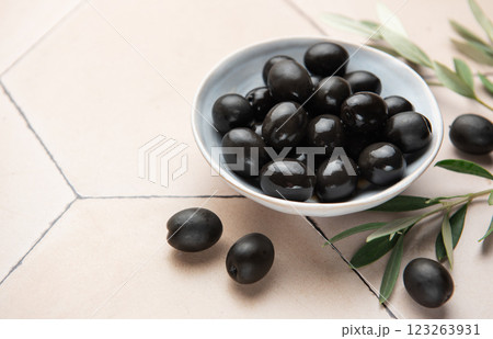 Black olives served in ceramic bowl on hexagonal beige tiles, decorated with olive tree branch Black olives served in ceramic bowl on hexagonal beige tiles, decorated with olive tree branch 123263931