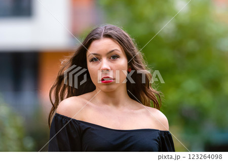Young Woman With Long Hair Wearing Black Top in Outdoor Urban Setting 123264098