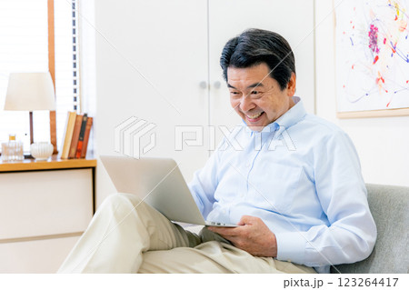 スマホとパソコンを操作するシニア男性 123264417