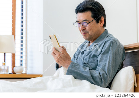 ベッドでスマホを使う中高年男性　眼鏡 123264426