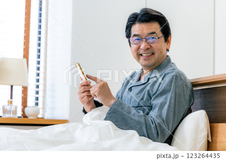ベッドでスマホを使う中高年男性　眼鏡 123264435