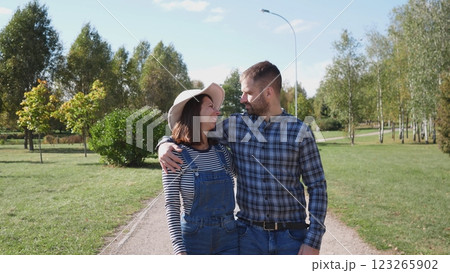 A joyful couple happily shares a special moment together while casually strolling hand in hand in a beautiful park A joyful couple happily shares a special moment together while casually strolling hand in hand in a beautiful park 123265902