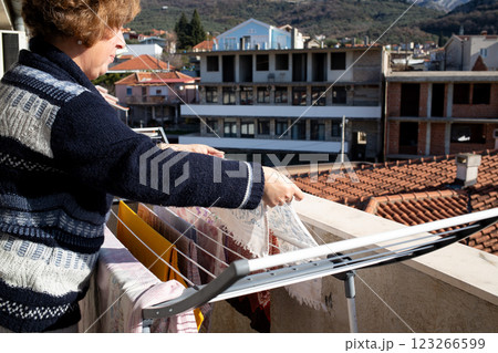 Woman hanging laundry on a terrace in the sunlight, energy conservation. 123266599