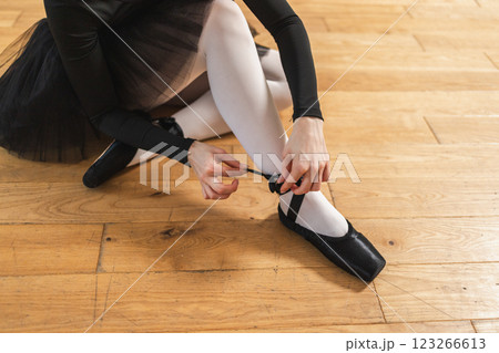 Ballerina puts on pointe shoes on leg in dance class. Classical ballet dancer woman in dance studio. Ballerina putting on tying classical pointe shoes for dance training. Ballet school concept Ballerina puts on pointe shoes on leg in dance class. Classical ballet dancer woman in dance studio. Ballerina putting on tying classical pointe shoes for dance training. Ballet school concept 123266613