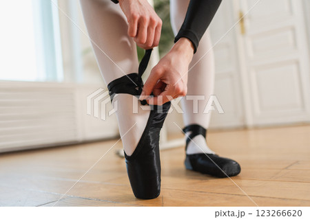 Ballerina puts on pointe shoes on leg in dance class. Classical ballet dancer woman in dance studio. Ballerina putting on tying classical pointe shoes for dance training. Ballet school concept Ballerina puts on pointe shoes on leg in dance class. Classical ballet dancer woman in dance studio. Ballerina putting on tying classical pointe shoes for dance training. Ballet school concept 123266620