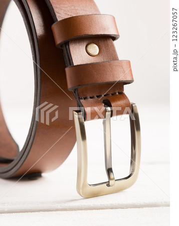 Brown leather belt on a white wooden background. 123267057