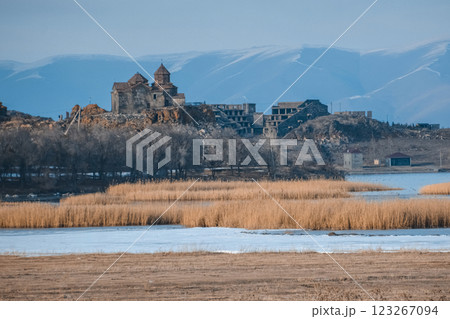 Monastery on the lake shore. Churches on the river bank. Winter landscape with church and lake. Monastery in nature. Frozen lake and rocky mountains	 123267094