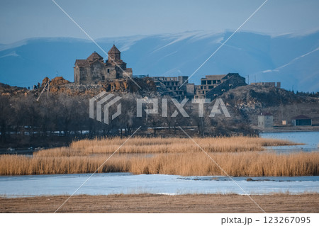 Monastery on the lake shore. Churches on the river bank. Winter landscape with church and lake. Monastery in nature. Frozen lake and rocky mountains	 123267095