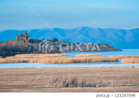 Monastery on the lake shore. Churches on the river bank. Winter landscape with church and lake. Monastery in nature. Frozen lake and rocky mountains	 123267096