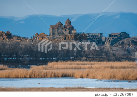 Monastery on the lake shore. Churches on the river bank. Winter landscape with church and lake. Monastery in nature. Frozen lake and rocky mountains	 123267097
