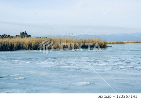 Monastery on the lake shore. Churches on the river bank. Winter landscape with church and lake. Monastery in nature. Frozen lake and rocky mountains	 123267143