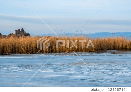 Monastery on the lake shore. Churches on the river bank. Winter landscape with church and lake. Monastery in nature. Frozen lake and rocky mountains	 123267144