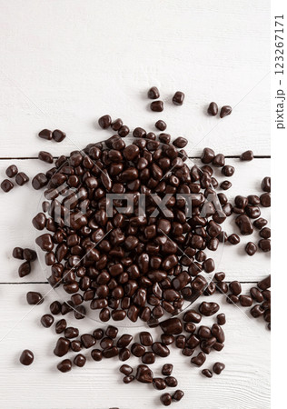 Dried fruits in brown chocolate. Candies on a white wooden background. Dried fruits in brown chocolate. Candies on a white wooden background. 123267171