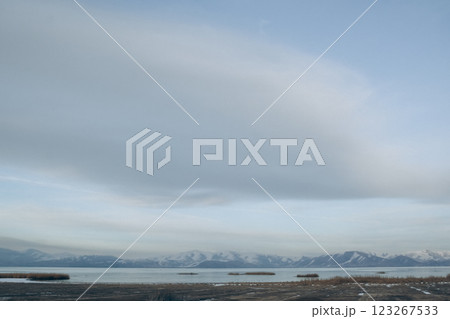Big cloud in the blue sky. Beautiful winter landscape with lake and mountains. Frozen lake and snowy mountains 123267533