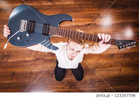 Proud man raising his electric guitar Proud man raising his electric guitar 123267596