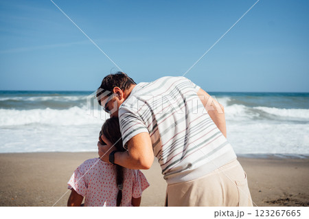 A father holds his daughter as they look out to the sea, enjoying the peaceful view and nature 123267665