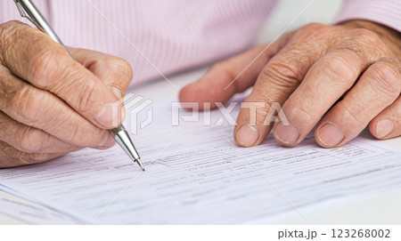 Close up of hands writing on document with pen, showcasing focus and diligence 123268002