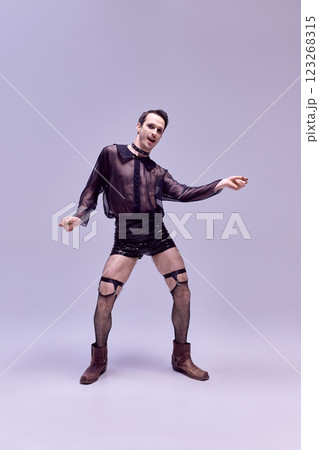 Artistic man, fashion-forward model in bold stylish outfit, dancing, embodying confidence and self-love against white studio background. 123268315
