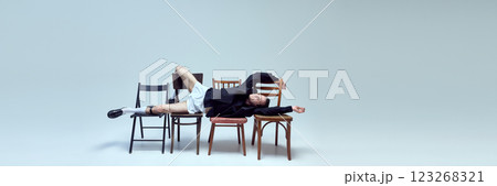 Banner. Stylish young man reclining across chairs with relaxed pose and playful confidence against white background with copy space. 123268321